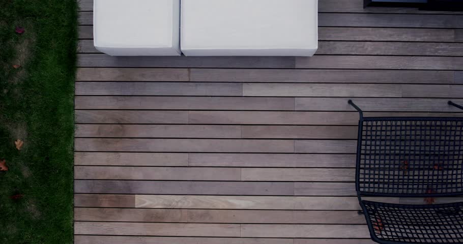 Modern patio furniture on a wooden deck. White cushioned sofas offer comfortable seating and two black metal chairs provide additional seating on the deck.