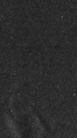 Black kraft paper noise texture vertical stop motion video. Old page overlay effect background loop animation. Vintage paper texture with crease, stain, grain, dust particles. Empty animated backdrop 