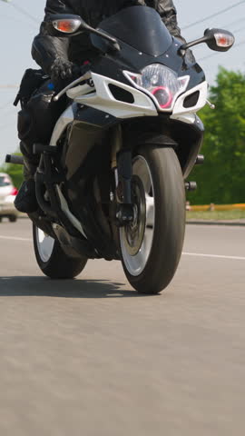 Couple enjoys contemporary motorcycle riding along highway against green trees at countryside on sunny summer day slow motion closeup