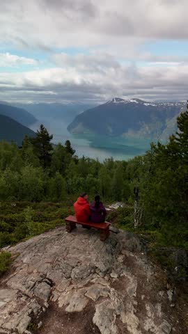 A couple sits peacefully on a rustic bench, immersed in the tranquil beauty of Norways fjords. Molden hike in Norway