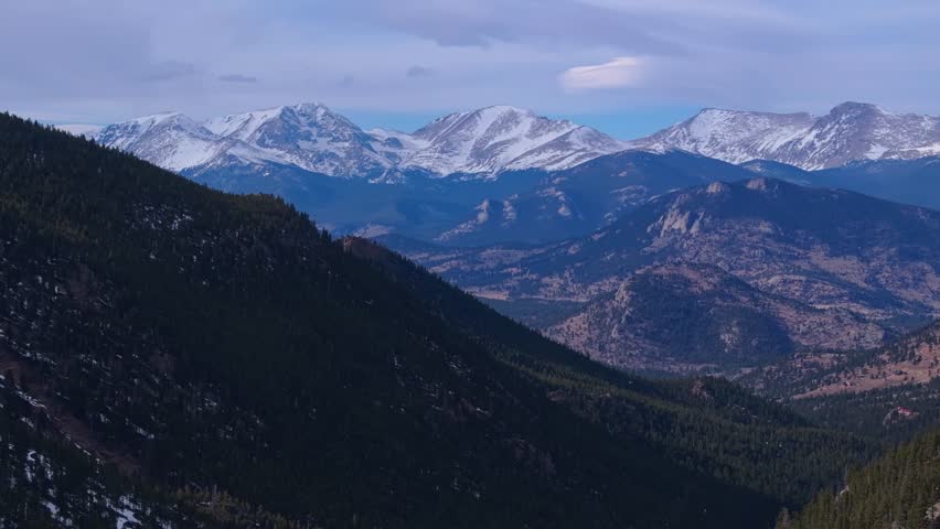 Mountain trail flanked by trees and snow lines runs across high forested terrain, Allenspark Colorado USA