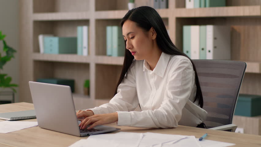 Thoughtful suffering sad Asian Japanese office worker manager business woman Chinese Korean female businesswoman entrepreneur working laptop suffer headache holding head eyestrain pain dry eye indoor