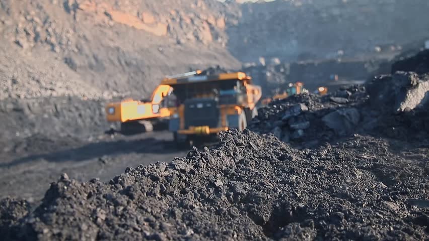 Excavator and dump truck in motion at coal open pit mining site. Mining blur background concept