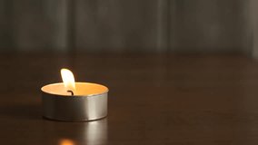 A small candle flickers softly while sitting on a wooden table. The warm glow fills the dimly lit room, creating an inviting atmosphere for relaxation. - Powered by Shutterstock - Get 15% off with code: PIKWIZARD15