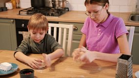 Teen Girl cooking pizza with brother. Little 6 years boy cooking pizza with sister in the kitchen. Children rolling up the dough, adding cheese, smear sauce. Kids making homemade pizza. Child baker - Powered by Shutterstock - Get 15% off with code: PIKWIZARD15