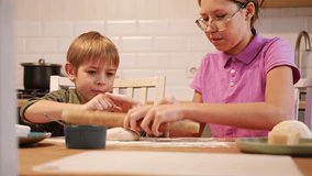 Teen Girl cooking pizza with brother. Little 6 years boy cooking pizza with sister in the kitchen. Children rolling up the dough, adding cheese, smear sauce. Kids making homemade pizza. Child baker - Powered by Shutterstock - Get 15% off with code: PIKWIZARD15