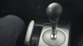 rear view of driver pushing gear lever into park then lifting hand brake lever on center console inside car cabin close up showing safe parking procedure with grip metal finish detail - Powered by Shutterstock - Get 15% off with code: PIKWIZARD15