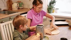 Teen Girl cooking pizza with brother. Little 6 years boy cooking pizza with sister in the kitchen. Children rolling up the dough, adding cheese, smear sauce. Kids making homemade pizza. Child baker - Powered by Shutterstock - Get 15% off with code: PIKWIZARD15