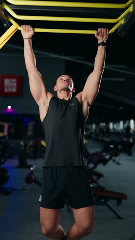 Muscular man doing pull-ups in a modern gym. He demonstrates strength, fitness, and determination as he completes each repetition. The gym environment adds to the energetic atmosphere.