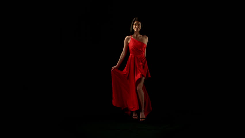 Brunette Woman in Ruby Red Dress Posing Against a Black Background . Filmed on High Speed Cinematic Camera in Super Slow Motion