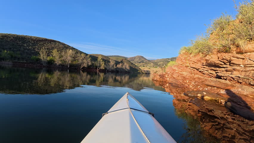 First person POV from springtime paddling a kayak or canoe along a sandstone cliff of Horsetooth Reservoir in Colorado