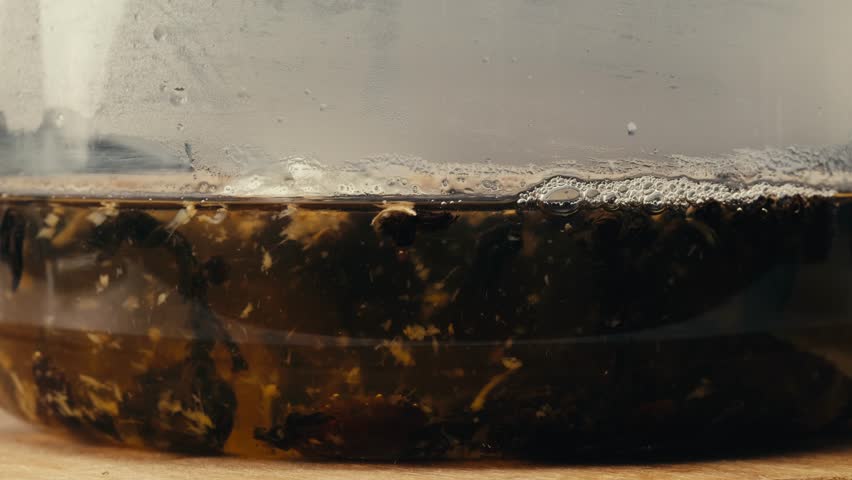 Ginger tea, freshly brewed black organic herbal tea with ginger, mint and lemon in a glass teapot, medication healthy.