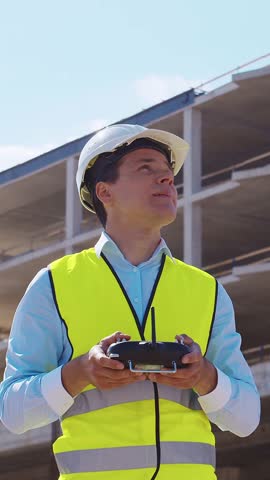 Professional builder standing in front of construction site. Foreman in hardhat helmet and vest. Office building and crane background. Business, real estate and investment.