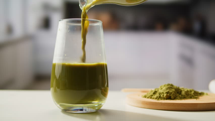 Matcha green tea cooking process, japanese powder green tea in a bowl with bamboo whisk, macro close up in cafe of powder green tea. 