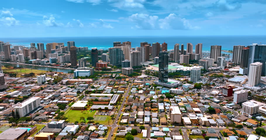 Sunny cityscape of modern Honolulu, Hawaii, USA. High-rise buildings of Waikiki at the backdrop of azure waterscape and sky. Aerial view.