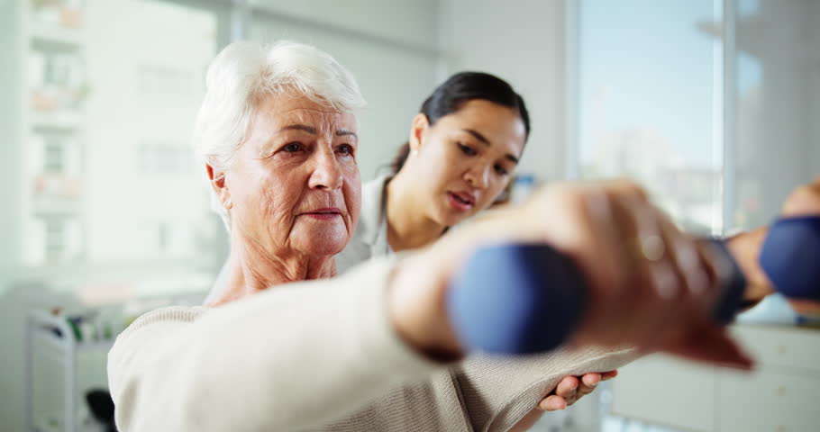 Elderly woman, physiotherapist and arms with weights for physical activity or muscle recovery at clinic. Senior, female person or therapist with patient or weightlifting for health rehabilitation