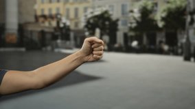 Man's hand making gesture outdoors in a city street backdrop, showing finger pointing down, then up, and finally thumbs up, with urban buildings blurred in background. - Powered by Shutterstock - Get 15% off with code: PIKWIZARD15
