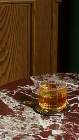  Close-Up of Hand Picking Up a Glass of Whisky in 4K Ultra HD – Elegant Bar Scene Featuring Amber Liquor, Ice Cubes, and Sophisticated Atmosphere

