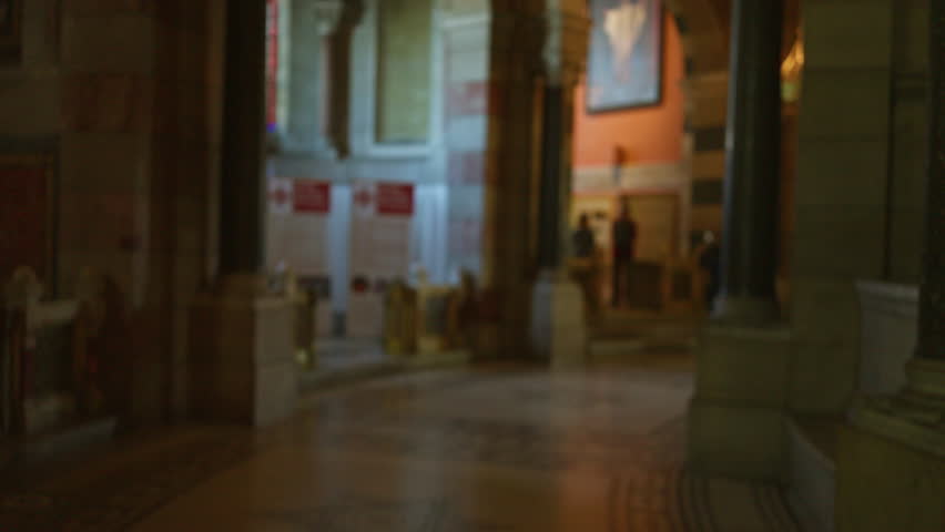 Church interior with blurred figures and ornate architecture in a dimly lit religious setting emphasizing a contemplative atmosphere with historic design.