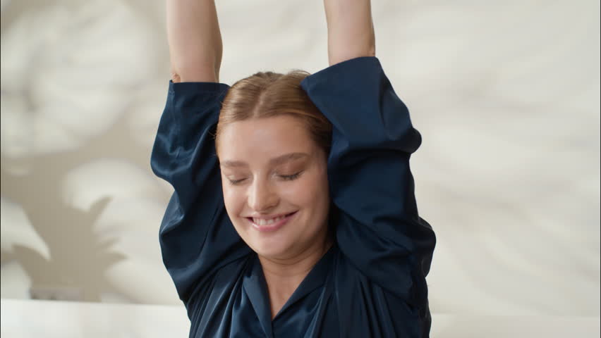 Carefree positive Caucasian girl stretching hands waking up morning cozy at home bedroom smiling adult female lying comfortable bed beauty treatment blanket woman rest weekend beautiful lady napping