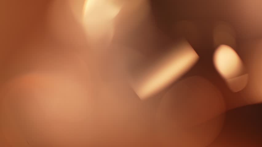 A warm-toned abstract blur image featuring a captivating lens flare effect, emanating a calming atmosphere. Slow motion.