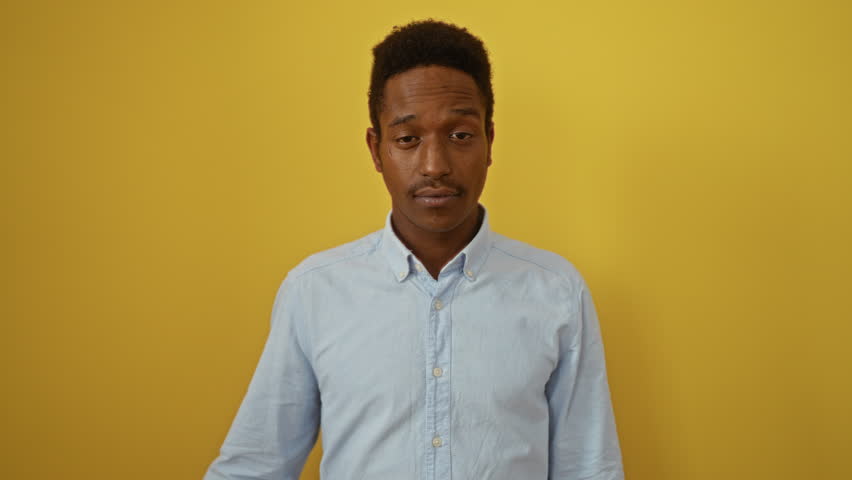 Young african american man wearing shirt, standing and smiling over isolated yellow background, pointing finger to head with great idea and good memory