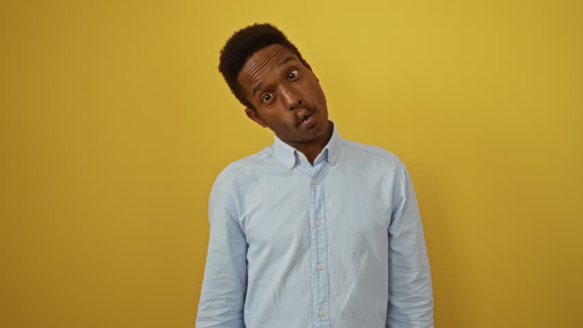 Young african american man wearing shirt standing with a fish face, making a funny, comical expression with lips over an isolated yellow background, crazy and fun gesture