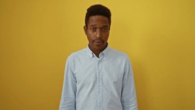 Young african american man wearing shirt standing pointing down, looking sad and unhappy, upset and depressed over isolated yellow background, indicating direction with his finger - Powered by Shutterstock - Get 15% off with code: PIKWIZARD15