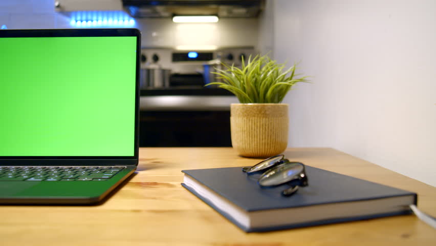 A High Resolution Closeup Of A Laptop With A Green Template Mockup Screen On A Sleek Wooden Desk In A Modern Kitchen Office, Perfect For Video Calls, Website Templates Or Game UI Previews.