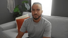 Young man with braids flexing on a couch in a modern apartment living room, exuding confidence and style. - Powered by Shutterstock - Get 15% off with code: PIKWIZARD15
