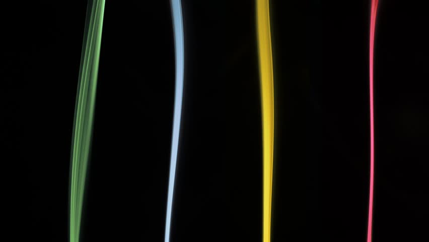 Vibrant colored light streams in green, blue, yellow, and red stand out against a dark backdrop, creating a striking visual effect. Slow motion