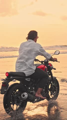 Person Riding Bike in Summer Landscape of Beach Traveling in Outdoors Nature. Handsome Motorcyclist or Surfer Driving Motorcycle in Speed Shot. Lifestyle of Alone Man in Motion on Stylish Transport