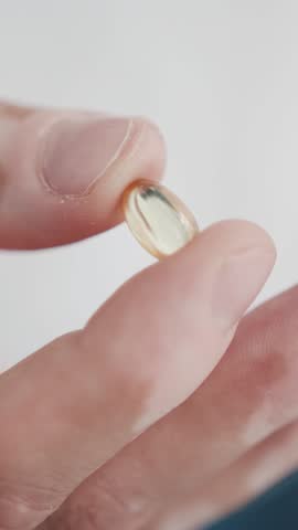 One Male Hand Holding Pill Yellow Omega 3 Gel Capsule Close-up. Pill Fish Oil Supplement. Concept of Health Care Vitamin and Medicine. Omega 3 Fish Oil Capsules, Vitamin D for Man Wellbeing Life 4k