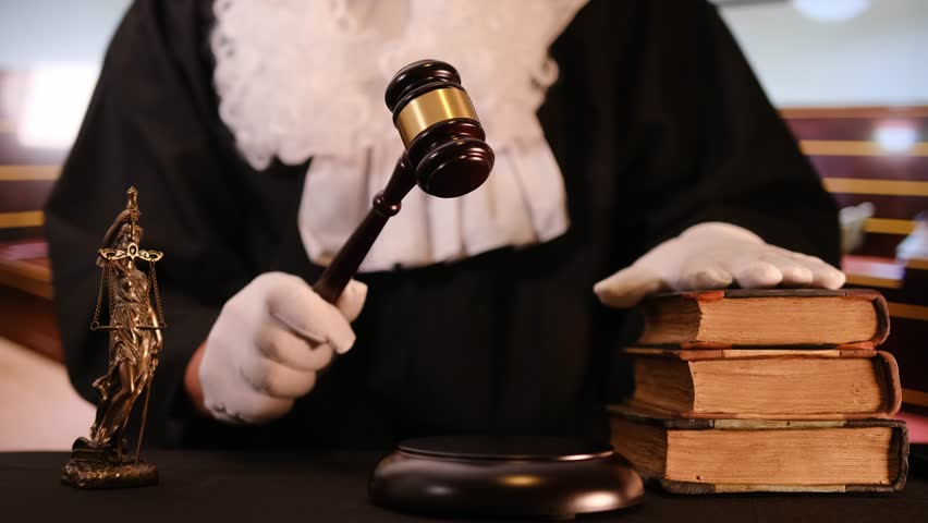A gavel strikes down in a courtroom setting, symbolizing justice and legal authority with law books