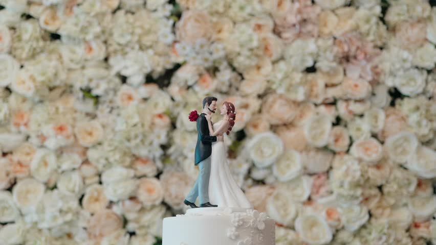 Bride and groom figurine on cake with soft floral background