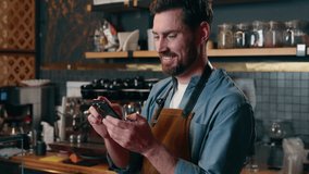 Happy Caucasian barista worker waiter guy scroll screen mobile phone employee male laughing in cafeteria bartender man typing smartphone cyberspace online small business Internet shopping social media - Powered by Shutterstock - Get 15% off with code: PIKWIZARD15