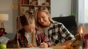 Cheerful Caucasian daughter little kid girl student writing copybook schoolgirl pupil solving school exercise woman mother teaching mom female tutor at home family parent child doing homework together - Powered by Shutterstock - Get 15% off with code: PIKWIZARD15