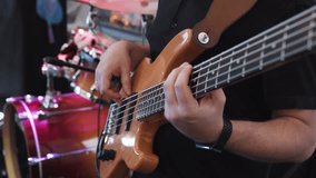 Bass guitarist bassist plays bass guitar during performance at party, concert. Close-up, hands of bass guitarist professionally play pop or rock music on electric bass guitar. Concert lighting - Powered by Shutterstock - Get 15% off with code: PIKWIZARD15