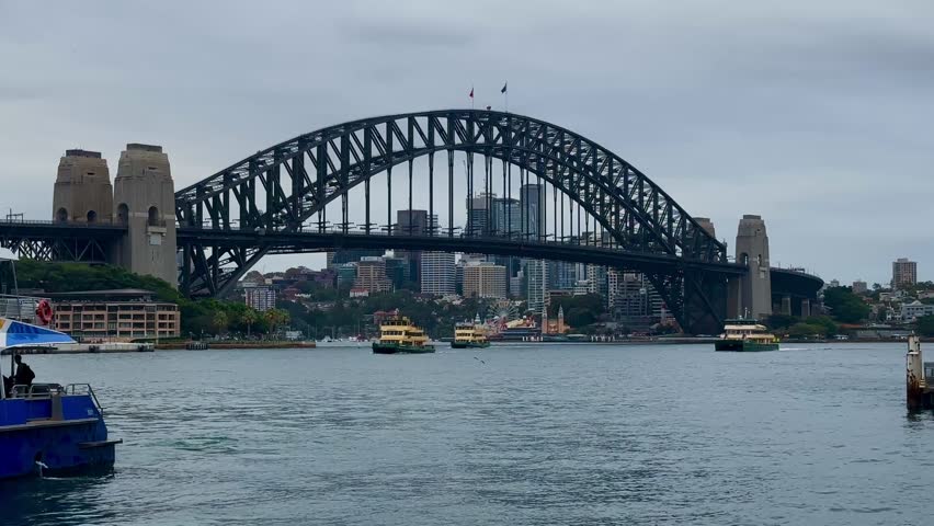 Sydney , NSW , Australia - 02 25 2025: Harbour Bridge Port Jackson Bay overcast yellow tugboats