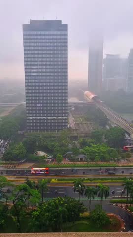 A sleek Jakarta MRT train soars above the bustling city, framed by tropical greenery and towering skyscrapers—urban speed meets natural beauty in Indonesia’s vibrant capital.