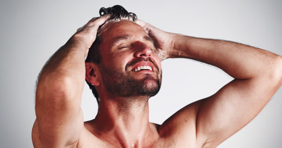 Hygiene, man or hair washing with shampoo for scalp cleansing, dandruff removal or grooming routine. Happy, person or self care with haircare product for healthy growth and shine on studio background
