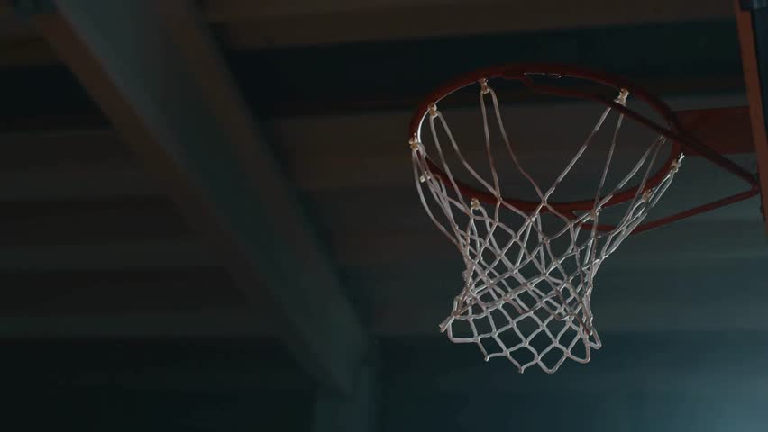 basketball hoop and shield at indoor sports arena. basketball ball hitting the basket during a game. Player throwing Basketball through the basket.