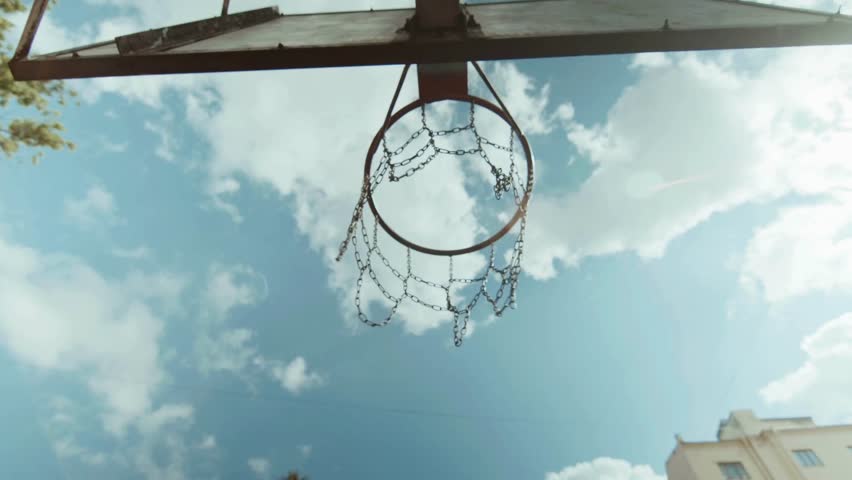 An old basket to play basketball on the background of daytime cloudy sky, shot from below. shot in basketball during the game at playground, Low angle view.