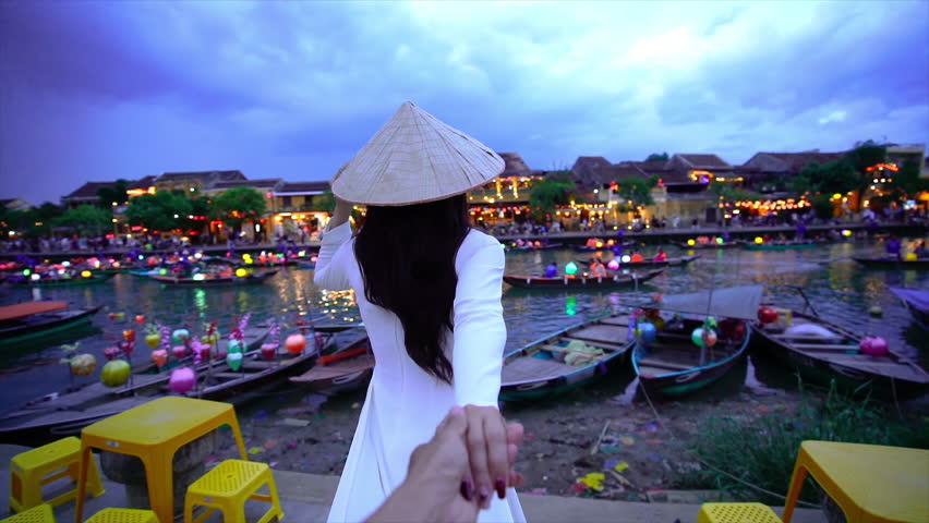 Women tourist holding man's hand and leading him to Hoi An ancient town,Hoi an city in Vietnam.