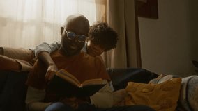 Heartwarming scene of African American father reading book with his child, capturing love, bonding, and peaceful family time on cozy afternoon - Powered by Shutterstock - Get 15% off with code: PIKWIZARD15