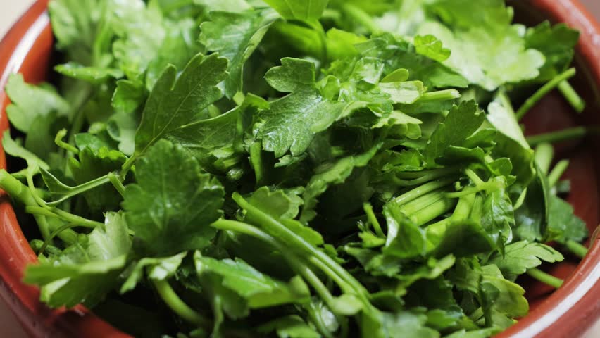 Finely chopped fresh herbs, parsley, dill and cilantro in a bowl ready for use in different dishes.