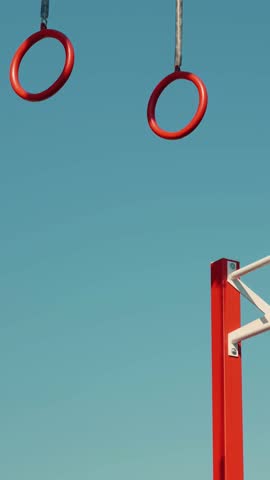 Male athlete exercising on gymnastic rings outdoors. Man practicing hard cardio endurance workout using gymnastic rings on sport ground. Vertical video