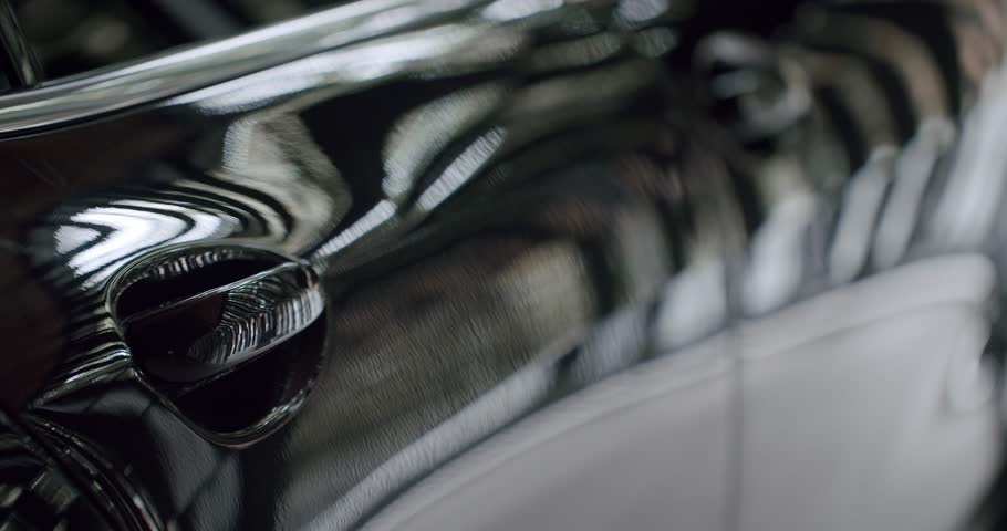 A close-up shot capturing the sleek and reflective surface of a luxury car. Ideal for conveying themes of elegance and high-end automotive design. Luxury Car Reflective Black Surface