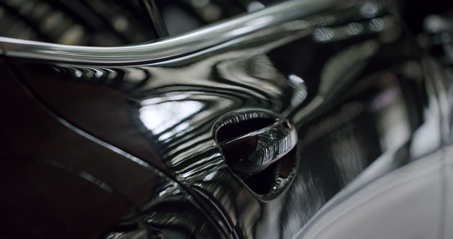 A close-up shot capturing the sleek and reflective surface of a luxury car. Ideal for conveying themes of elegance and high-end automotive design. Luxury Car Reflective Black Surface
