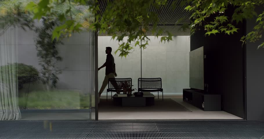 A man walks through a stylish, modern home interior featuring minimalist design, large glass windows, and lush outdoor views. Modern Home Interior with Man Walking in Minimalist Design